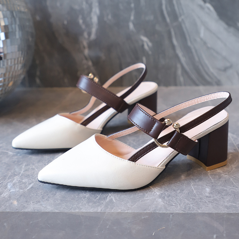 White shoes with brown straps on a gray surface