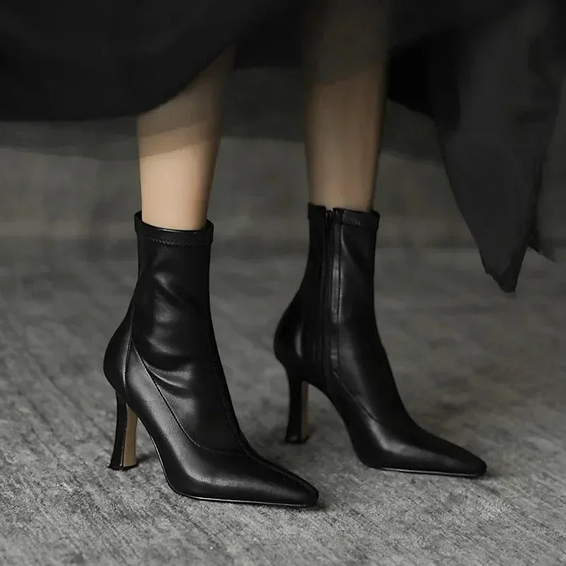 Black leather high-heeled ankle boots on a neutral background