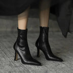 Black leather high-heeled ankle boots on a neutral background