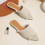 Pair of white slip-on shoes with brown soles on a light surface.