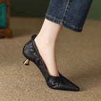 Black high-heeled shoes worn with denim jeans on a neutral background