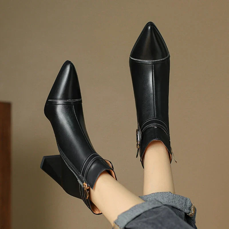 Black pointed-toe boots worn with a neutral background