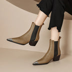 Brown ankle boots with metallic toe tips worn by a person on a beige background